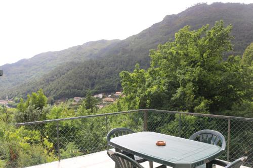 a table and chairs on a balcony with a mountain at Casinhas da Lu in Geres