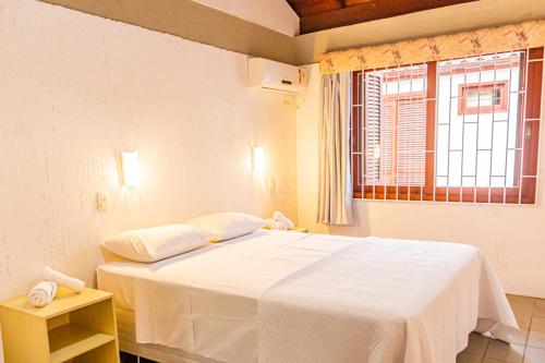 a white bed in a room with a window at Casa Geminada duplex 04, Jurerê a 3 quadras da praia JUR184 in Florianópolis