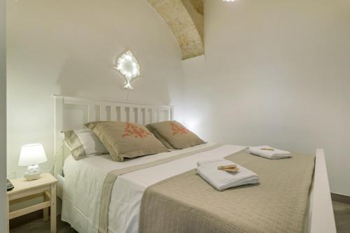 a white bedroom with two beds with towels on them at CIVETTHOUSE : la casa delle civette in Polignano a Mare