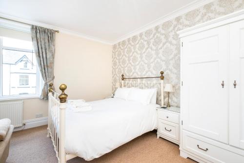 a white bedroom with a white bed and a window at Cragwood Guest House in Keswick