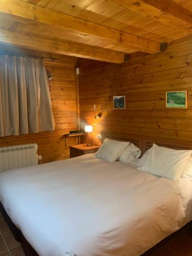 ein Schlafzimmer mit einem weißen Bett an einer Holzwand in der Unterkunft PANORAMIC - Peu del Riu 502 - Vall d'Incles - Soldeu in Incles