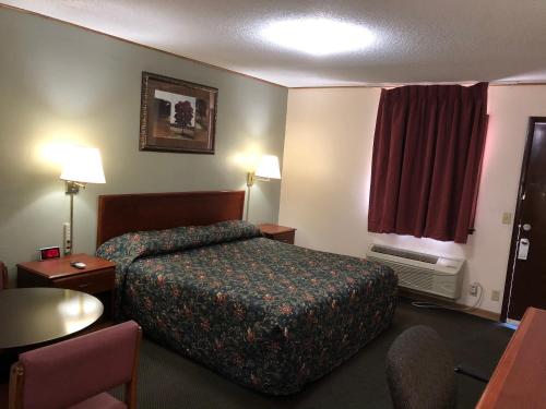 a hotel room with a bed and a chair at Budget Host Inn - Emporia in Emporia