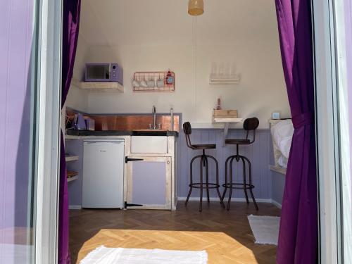 a kitchen with a table and two bar stools at Lilac Tree Hut in Tenby
