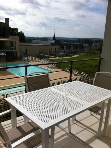 a white table on a balcony with a view of a pool at Résidence Odalys Le Clos Saint Michel in Chinon