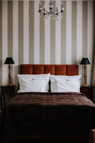 a bedroom with a bed with striped walls and a chandelier at Willa Sepia SPA in Wisła