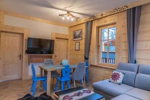 a living room with a blue couch and a table and chairs at Zbyszko Apartament Niebieski in Zakopane