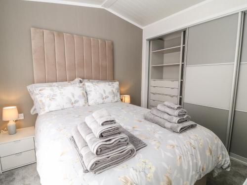 a bedroom with a white bed with towels on it at Dove Lodge in Beaworthy