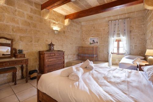 een slaapkamer met een groot bed en handdoeken bij Superb Maltese Farmhouse with Private Pool in Victoria