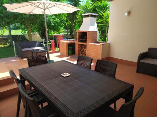 una mesa negra y sillas con sombrilla y chimenea en Casa da Nanda, en Crespos
