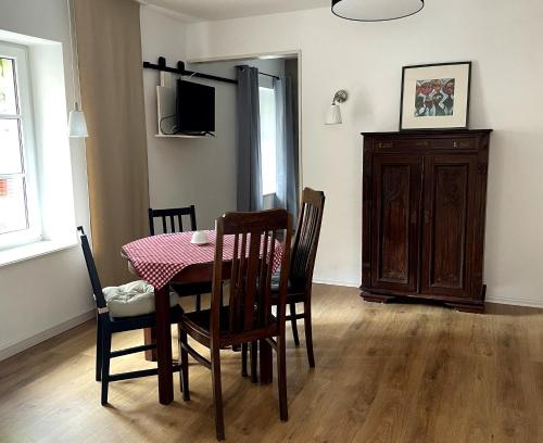 ein Esszimmer mit einem Tisch, Stühlen und einem TV in der Unterkunft FEWO im Kneipenviertel Altkötzschenbroda in Radebeul