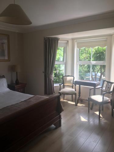 a bedroom with a bed and two chairs and a window at Barr's Guest Accommodation in Moville