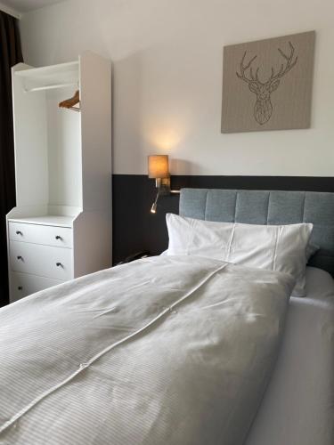 a bedroom with a white bed with a blue headboard at Hotel Haus am Hochwald in Hahnenklee-Bockswiese