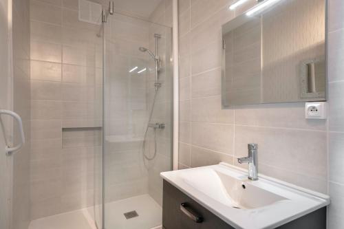 une salle de bain avec un lavabo et une douche avec un miroir dans l'établissement À 50m de la plage, appartement vue mer pour 5, à Pornichet