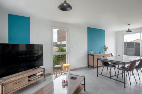 un salon avec une grande télévision et une table dans l'établissement Maison moderne pour 7 personnes à Saint-Michel-Chef-Chef, à Saint-Michel-Chef-Chef