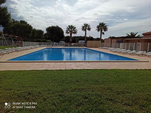 una gran piscina con sillas y palmeras en CARRO PROCHE MER MAISON DANS RESIDENCE 3 étoiles avec piscine et tennis, en Martigues