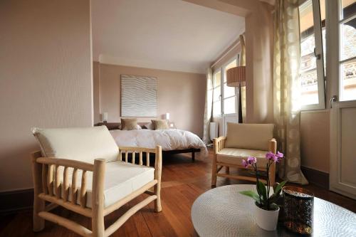 a bedroom with a bed and two chairs and a table at Le Balcon de Colmar in Colmar