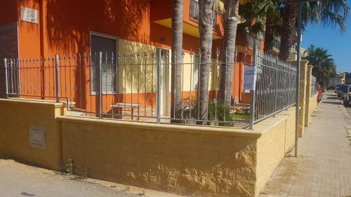 an orange building with a fence next to a sidewalk at Villa Lella in Marausa