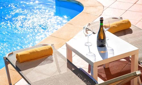 una botella de vino en una mesa junto a una piscina en Secret Escape Villa Heated Pool and Jacuzzi, en Kolimvárion