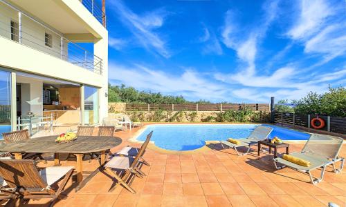 un patio con mesa y sillas junto a una piscina en Secret Escape Villa Heated Pool and Jacuzzi, en Kolimvárion