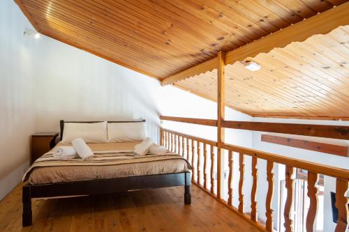 a bed in a room with a wooden ceiling at Kiki&Nina in Halki