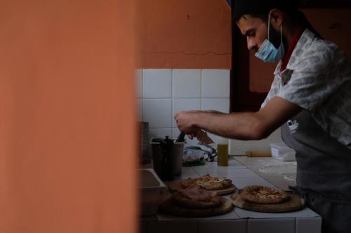 a man in a mask making pizzas on a counter at Masseria Sant'Agapito in Lucera