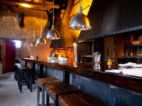 a restaurant with a bar with benches and pendant lights at The Singular Patagonia Hotel in Puerto Natales