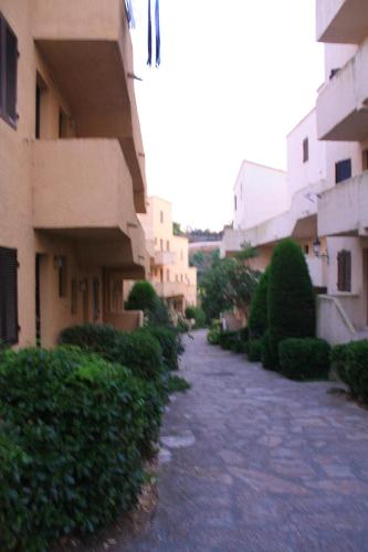 une allée entre deux bâtiments avec des buissons et des arbres dans l'établissement Appartement élégant à Grosseto-Prugna de 46 m² avec piscine partagée, à Grosseto-Prugna