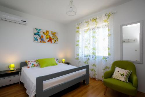 een slaapkamer met een bed en een groene stoel bij Apartments Jagoda in Vrbnik