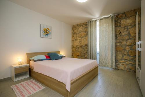 a bedroom with a bed and a stone wall at Oliva in Vrbnik