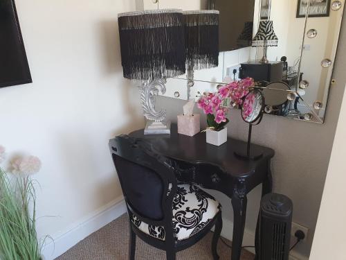 a black desk with a chair with a lamp and flowers at The Dudley Hotel in Blackpool