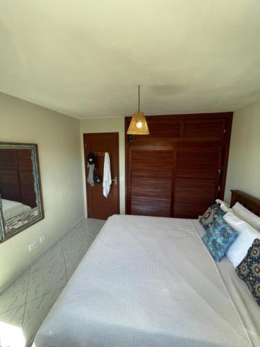 a bedroom with a large white bed with a wooden headboard at Casa Pipa Charme do Amor in Pipa