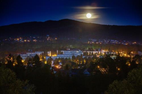 a full moon rising over a city at night at Zdrojowy Gościniec - domki Rabka-Zdrój in Rabka