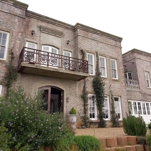 - un grand bâtiment en briques avec un balcon dans l'établissement Villa Anna Katarina, à Riebeek-Kasteel