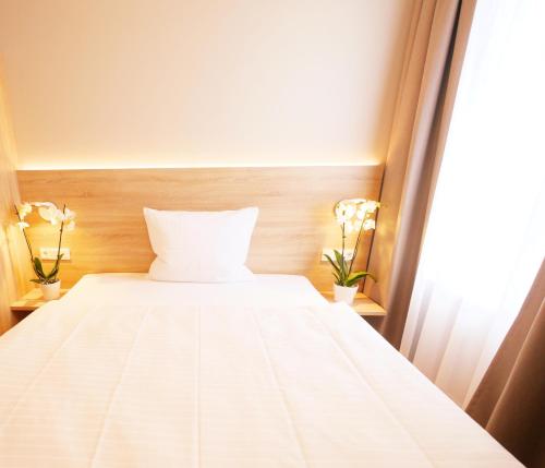 a white bed in a room with a window at KELKO 1A Hotel in Kehl am Rhein