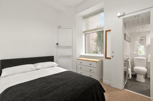 a bedroom with a bed and a toilet and a window at Bay Apartment in Helensburgh