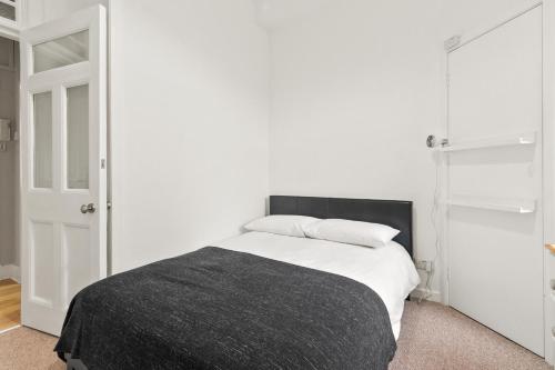 Bay Apartment في هيلينسبورغ: غرفة نوم بيضاء مع سرير وبطانية سوداء