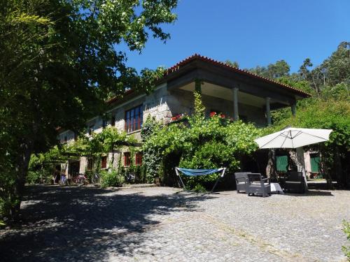 a house with an umbrella and a table and chairs at Quinta da Tapada in Longos