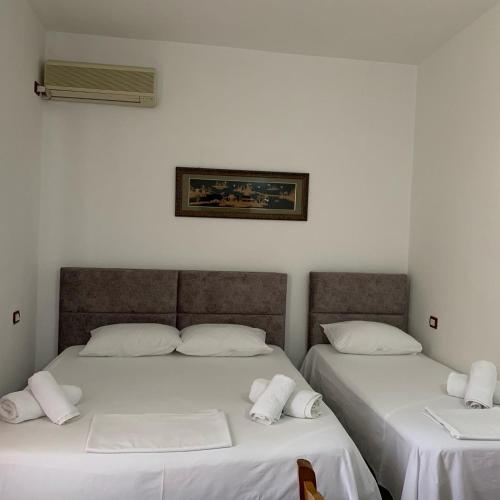 two beds in a room with white sheets at Red Rose Guest House in Golem