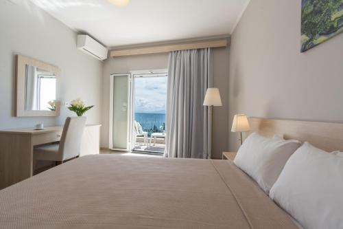 a bedroom with a bed and a desk and a window at Corfu Aquamarine in Nótos