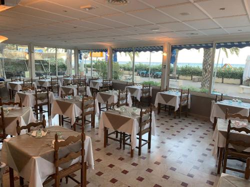 um restaurante com mesas e cadeiras brancas e janelas em Hotel Svizzera em Arma di Taggia