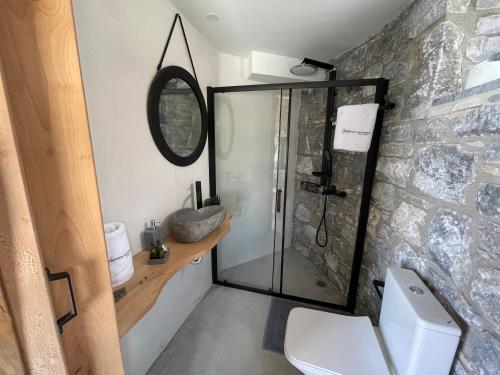 ein Bad mit einer Glasdusche und einem WC in der Unterkunft Windmills Village Amarynthos in Amarinthos