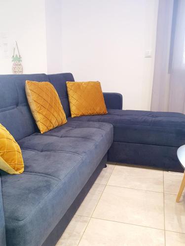 a blue couch with yellow pillows in a living room at Tom's House in Néa Karváli