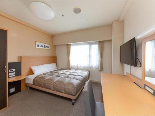 a bedroom with a bed and a flat screen tv at The OneFive Okayama - Vacation STAY 41846v in Okayama
