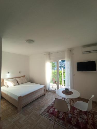 a bedroom with a bed and a table and a window at Lastva Holliday Rooms in Budva