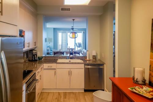 a kitchen with white cabinets and a large window at Beach Colony of Perdido West in Perdido Key