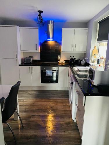 a kitchen with white cabinets and a black counter top at Port Pour Deux in Portrush