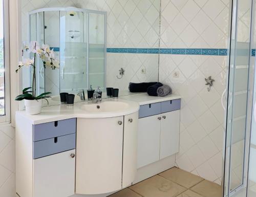 a white bathroom with a sink and a mirror at Maison avec vue panoramique in Cavalaire-sur-Mer