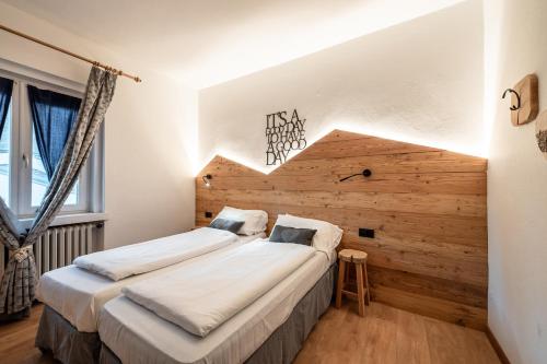a bedroom with two beds and a wooden wall at -Antermoia- Appartament Canazei Center in Canazei