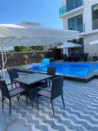 a patio with a table and chairs next to a pool at Aparthotel Alfa in Ureki
