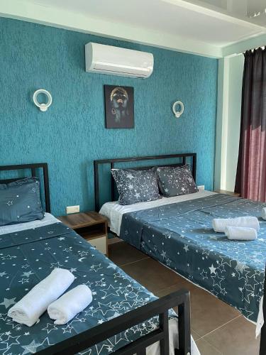 two beds in a room with blue walls at Aparthotel Alfa in Ureki